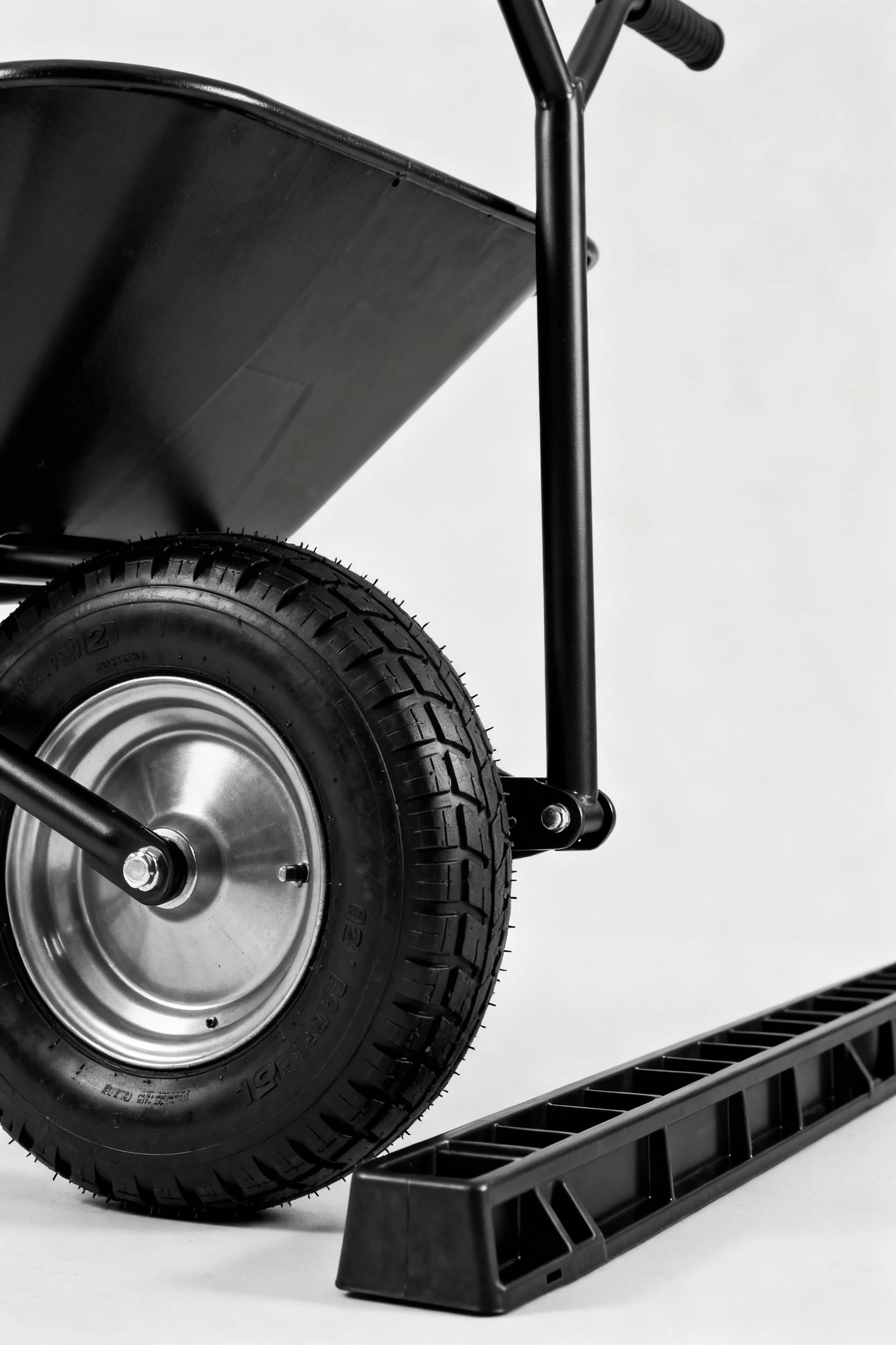 closeup black 12-inch pneumatic wheel, wheelbarrow handle, plastic skid rail