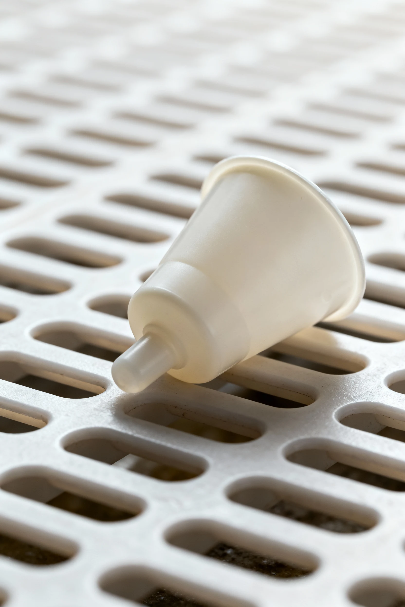 closeup gravity waterer nipple cup on plastic drain mat