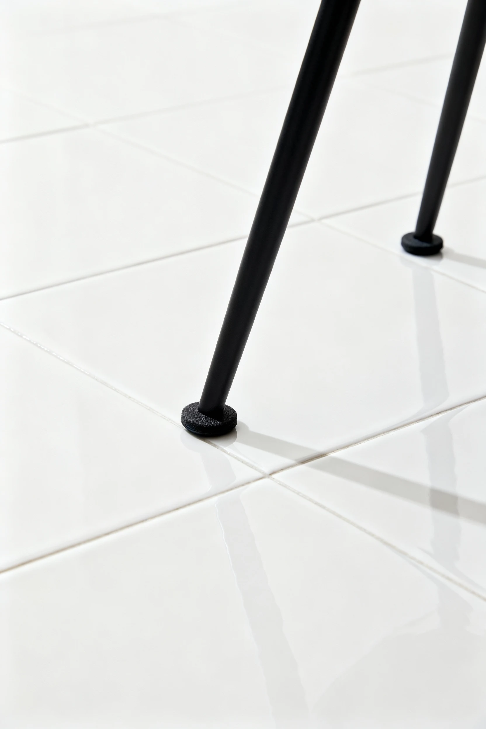 Closeup slim black chair legs with pads on porcelain paver
